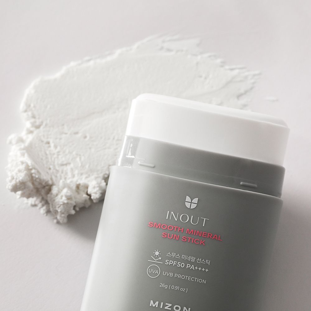 Stick solare e prodotto. Protezione solare bianca su sfondo bianco. Testo: INOUT, Smooth Mineral Sun Stick, MIZON.
