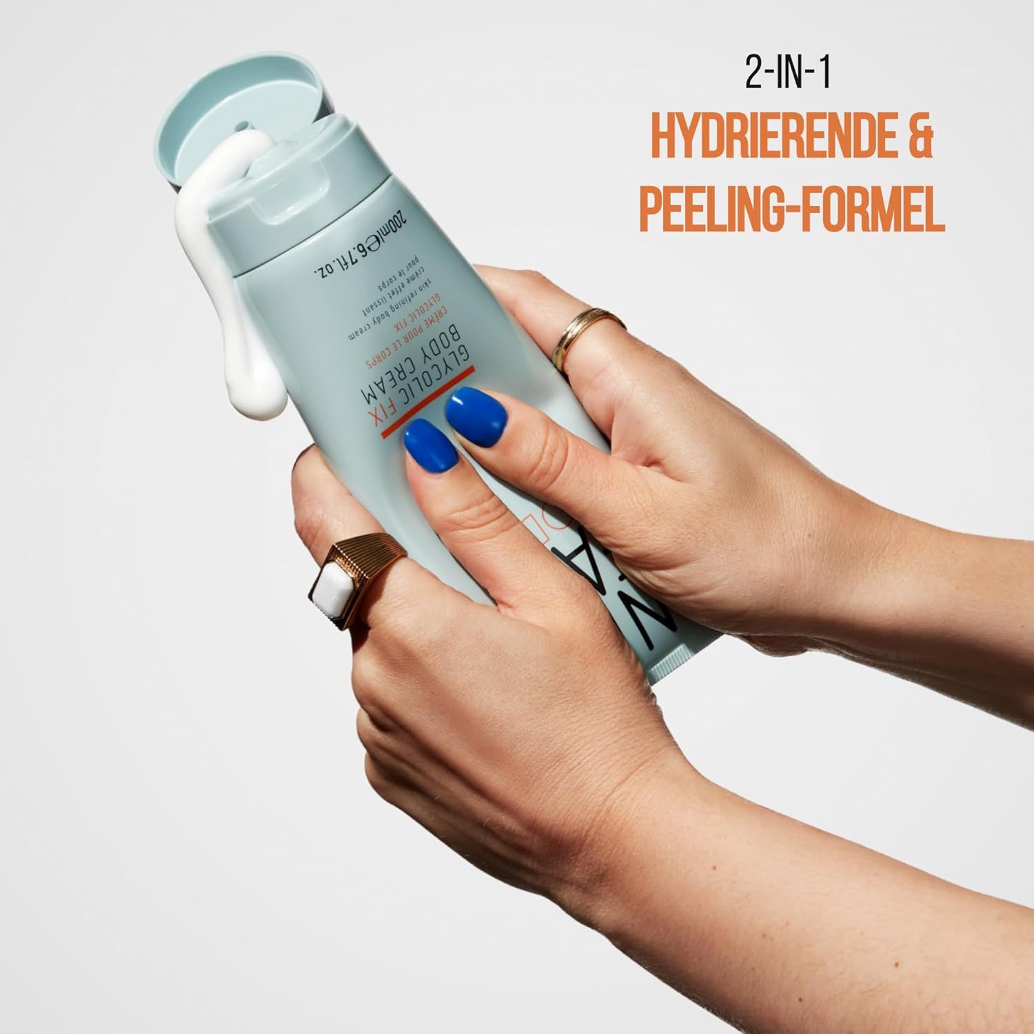 Mani che tengono un tubetto da cui fuoriesce la crema. Scritta: 2-IN-1 FORMULA IDRATANTE & PEELING.
