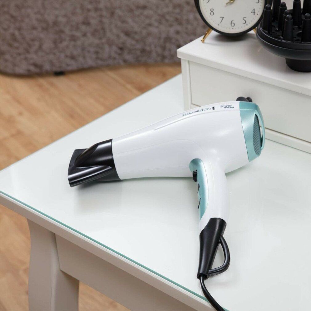 Asciugacapelli bianco su un tavolo. Marchio Remington. Dettagli blu. Cavo nero.