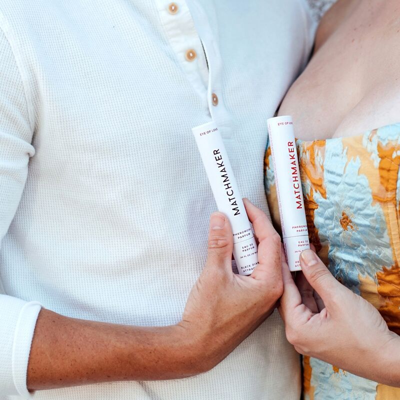 Due flaconi con liquido rosso. Scritta MATCHMAKER. Mani che tengono i flaconi. Sfondo: chiaro.