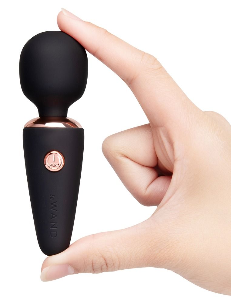 Vibratore viola con anello e pulsante oro rosa, in mano.