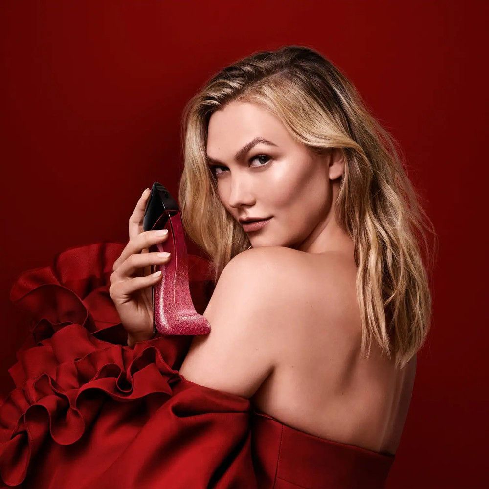 Donna che tiene il flacone di profumo Carolina Herrera Very Good Girl Glam a forma di scarpa.