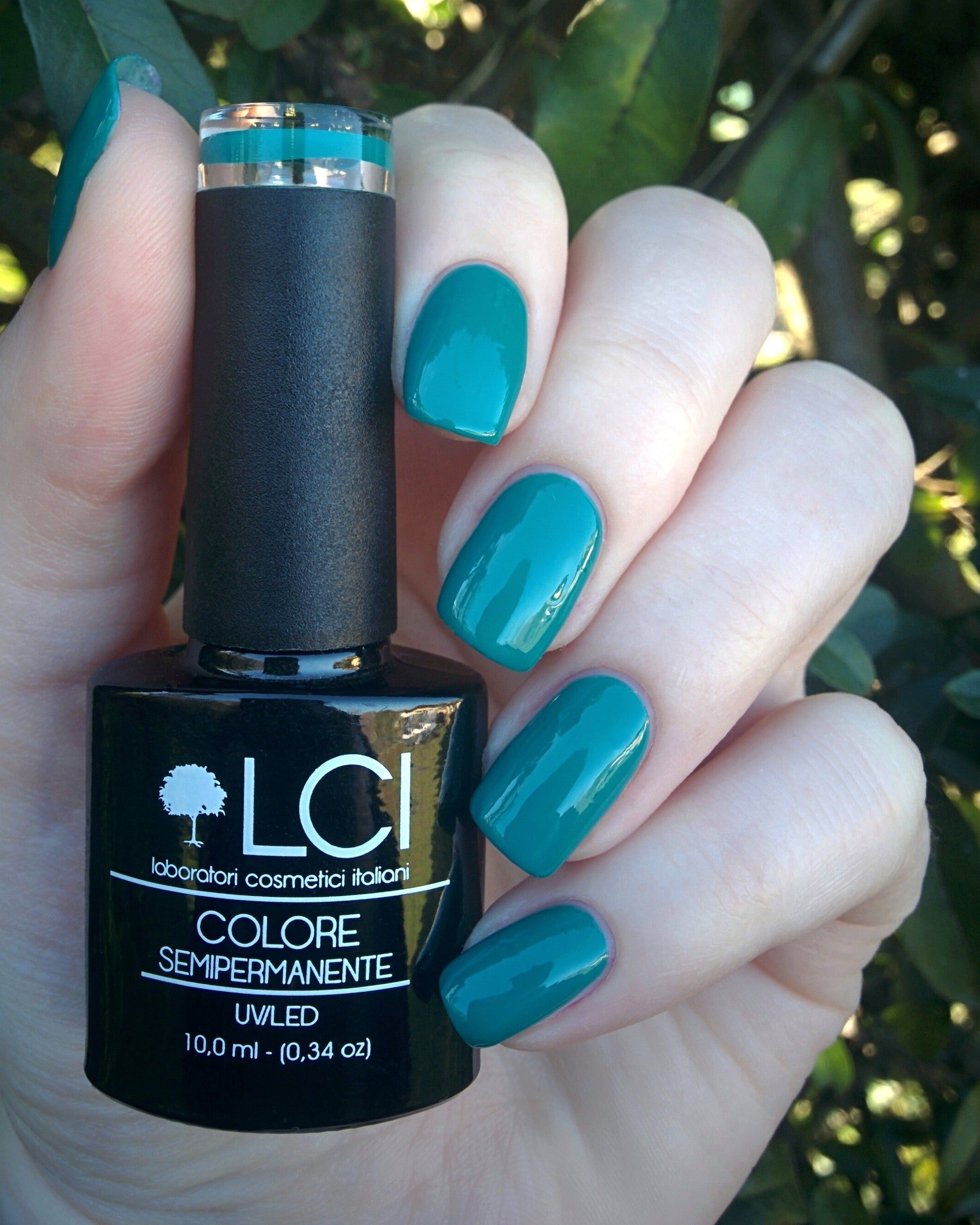 Flacone di smalto verde scuro in una mano che mostra unghie smaltate. Scritta: LCI, Colore Semipermanente, UVLED 10,0 ml.