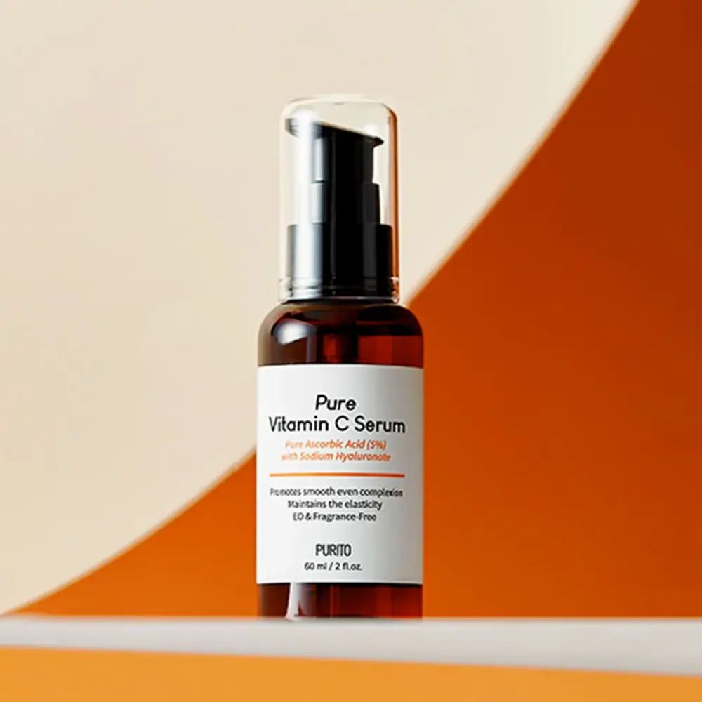 Flacone di siero marrone con erogatore nero. Scritta: Pure Vitamin C Serum. Sfondo: arancione.