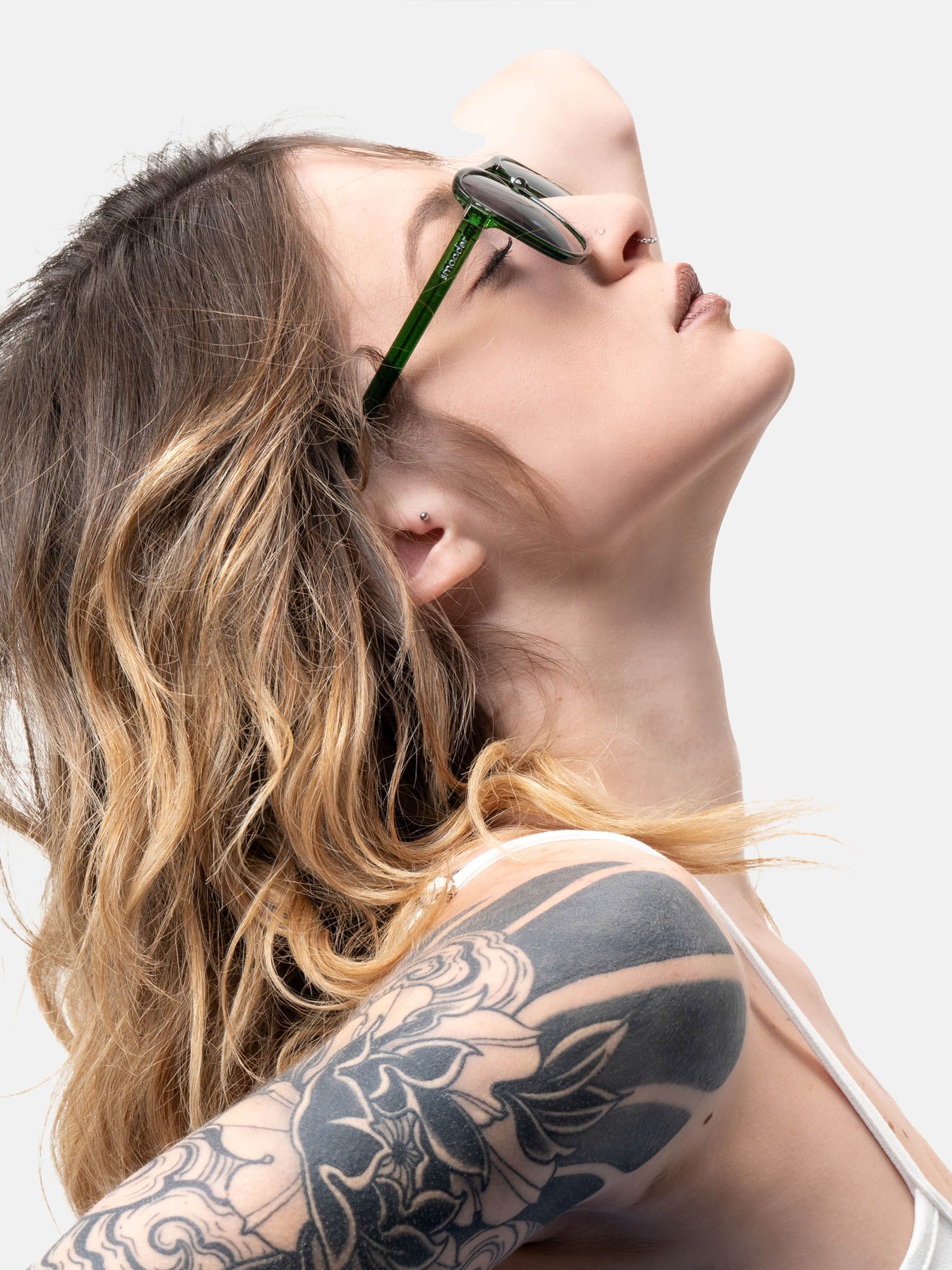 Persona con occhiali da sole Smooder. Montatura verde, lenti scure. Donna con tatuaggio e canotta.