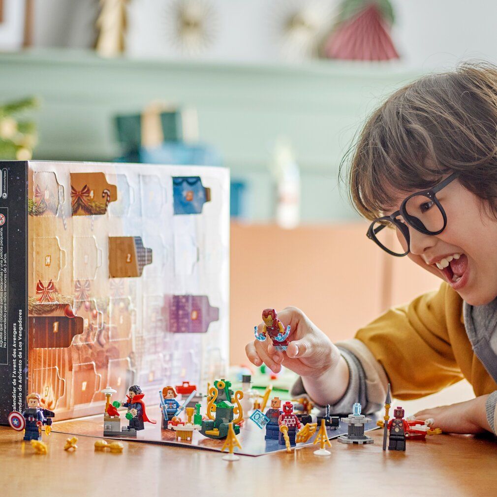 Bambino che gioca con il calendario dell'Avvento LEGO Marvel. Personaggi e scene sul tavolo. Include Iron Man, Spider-Man e Captain America.