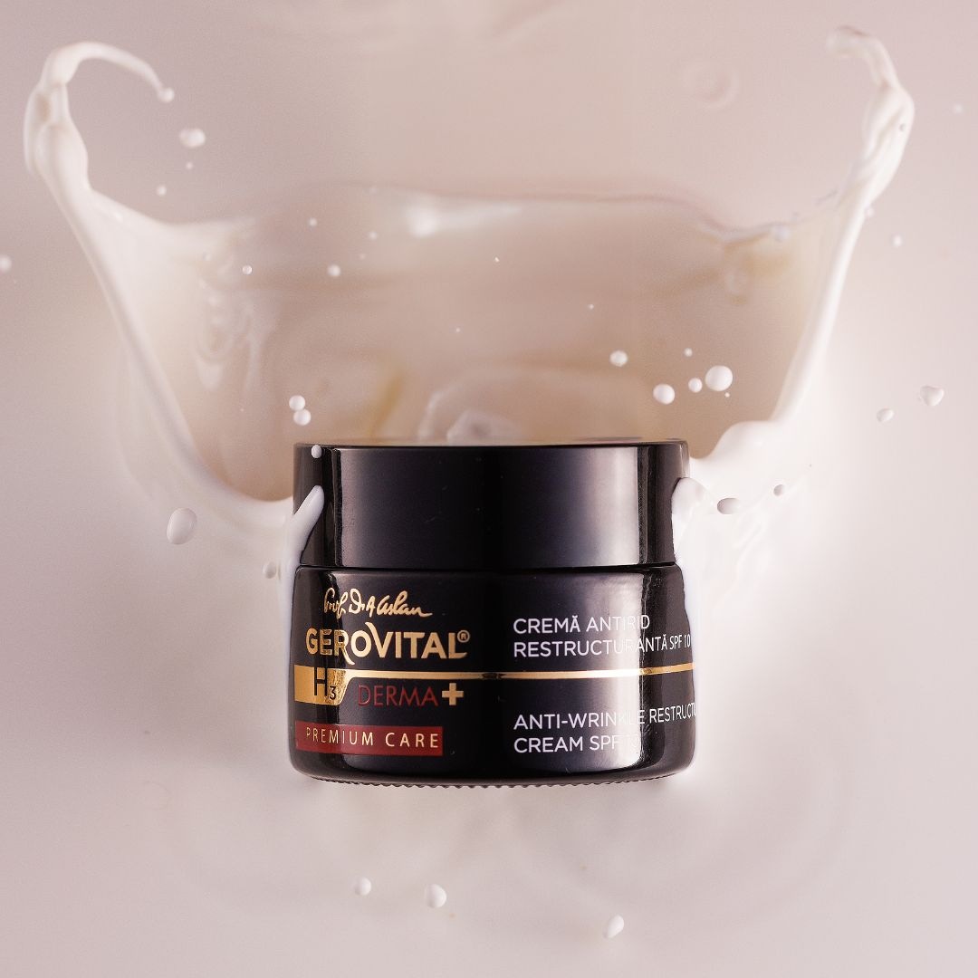 Vasetto nero di crema con crema bianca, circondato da schizzi di latte. Testo: Gerovital H3 Derma+, Crema ristrutturante anti-rughe SPF10.