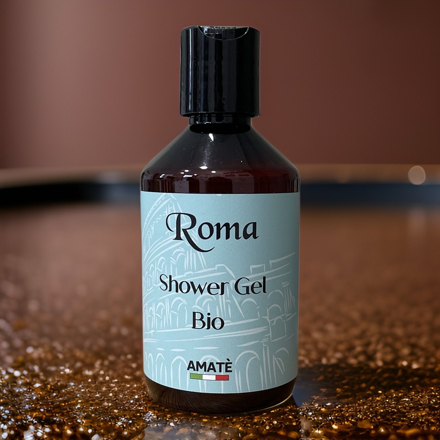 Flacone marrone con tappo nero. Etichetta: Roma, Shower Gel, Bio e Amatè. Su superficie lucida.