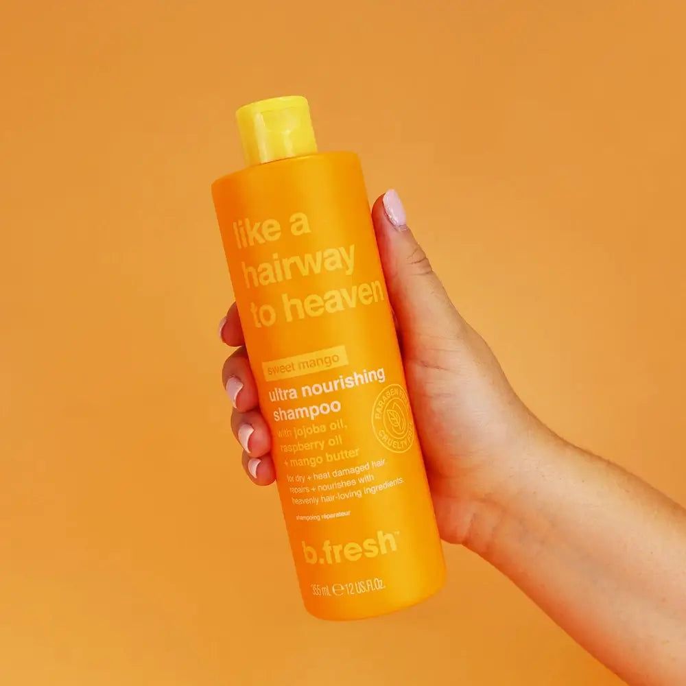 Flacone di shampoo arancione tenuto in mano. Scritta: "like a hairway to heaven" e "b.fresh".
