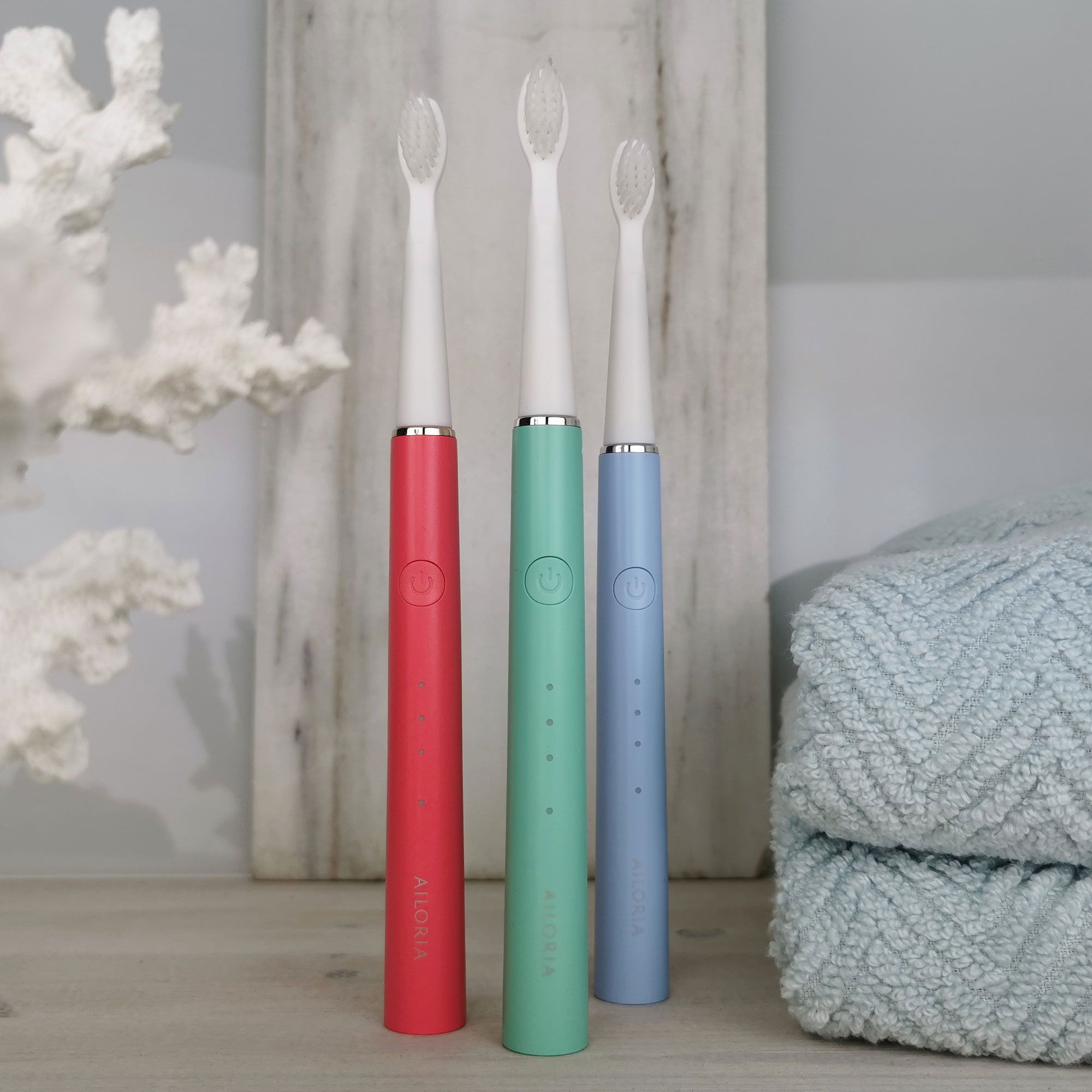 Tre spazzolini sonici in rosso, verde e blu. AILORIA su ognuno.