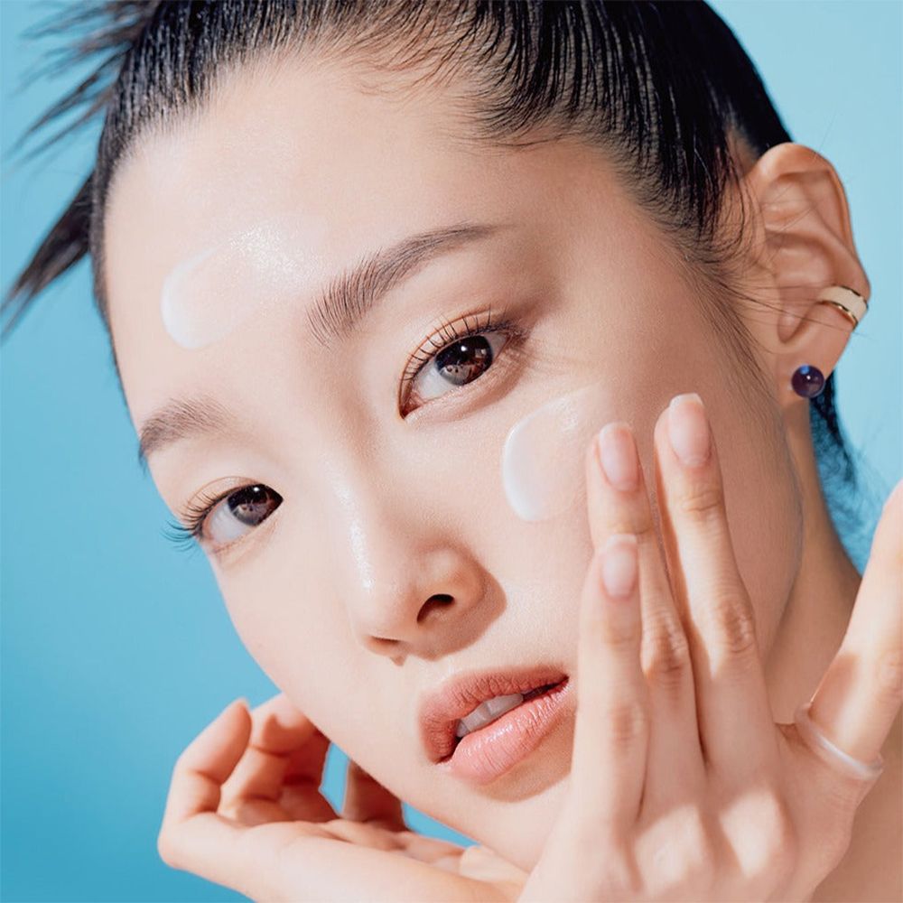 Donna applica crema solare sul viso. Prodotto non identificabile.