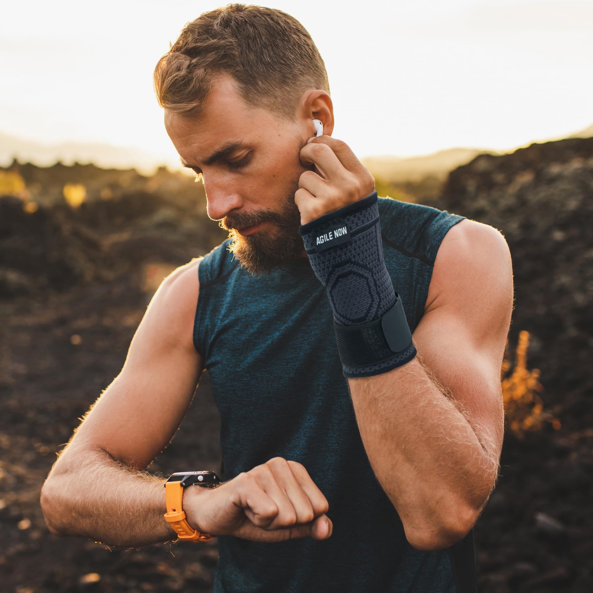 Uomo con tutore per polso mentre fa jogging. Nero. Testo: AGILE NOW. Con auricolari e smartwatch.