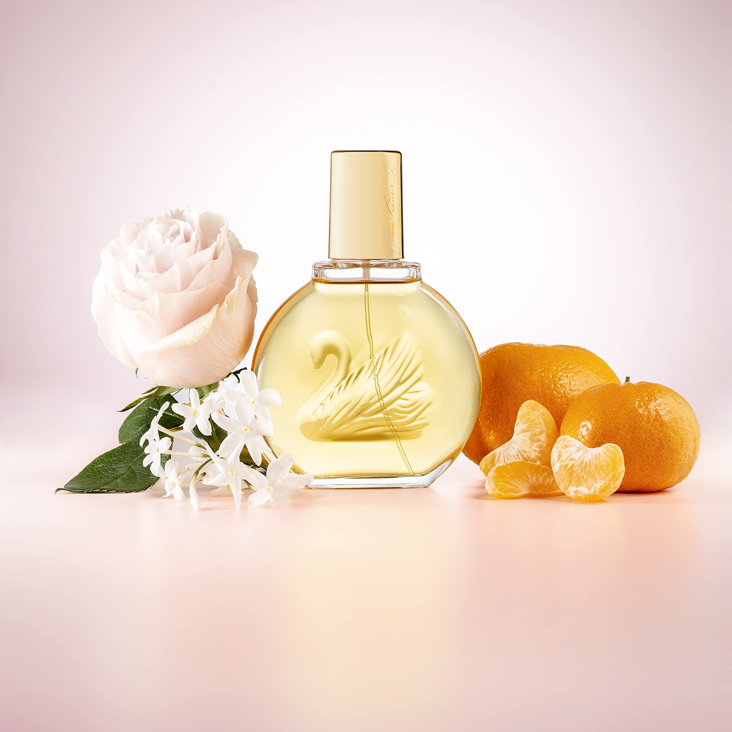 Flacone di profumo, rosa, mandarini. Flacone rotondo, tappo dorato. Rosa e mandarini accanto.