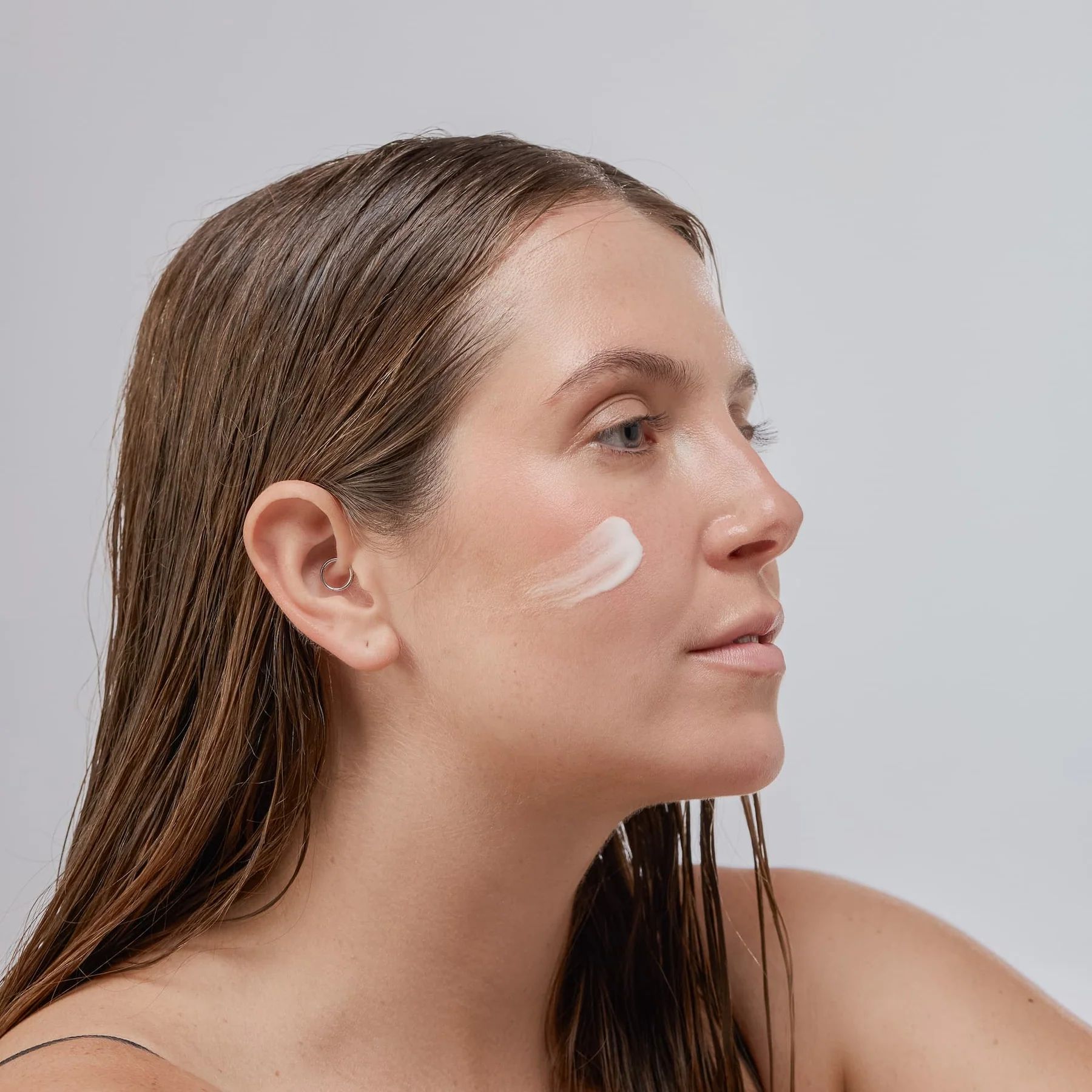Donna con siero sul viso. Siero applicato sulla pelle. Sfondo chiaro.