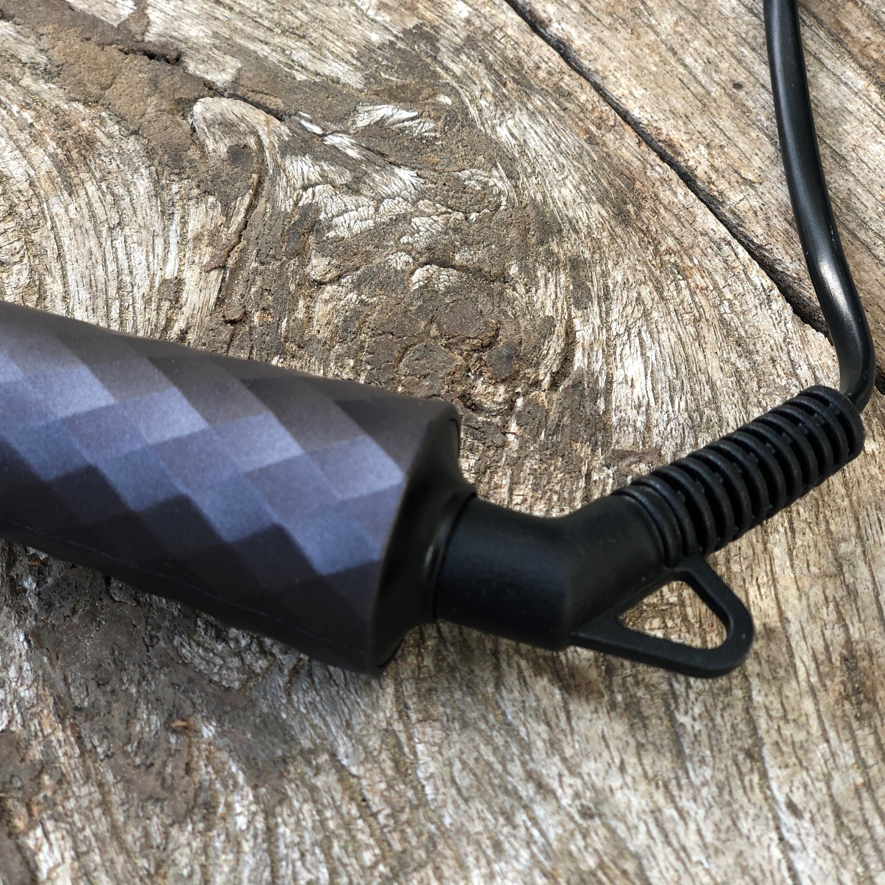 Primo piano dell'arricciacapelli nero. Motivo geometrico sull'impugnatura. Attacco cavo.