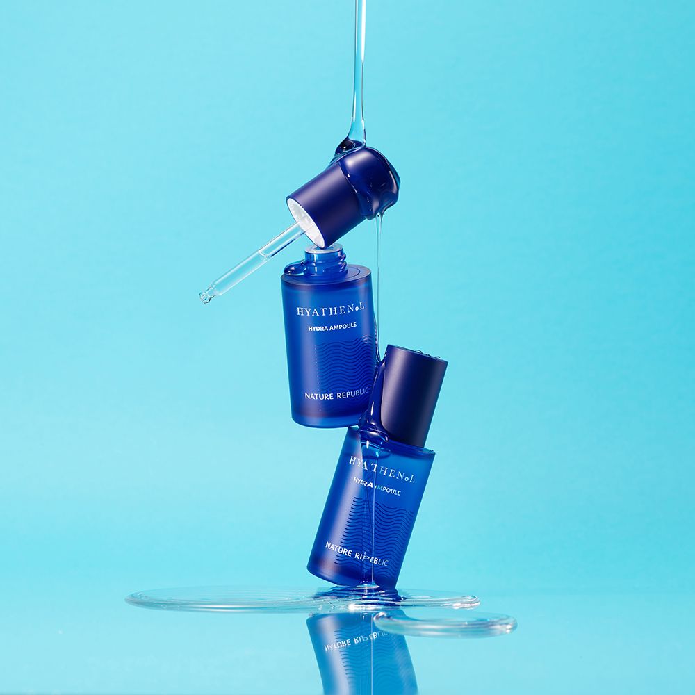 Due flaconi di siero blu. Scritta: HYATHENOL Hydra Ampoule, NATURE REPUBLIC. Gocce d'acqua.