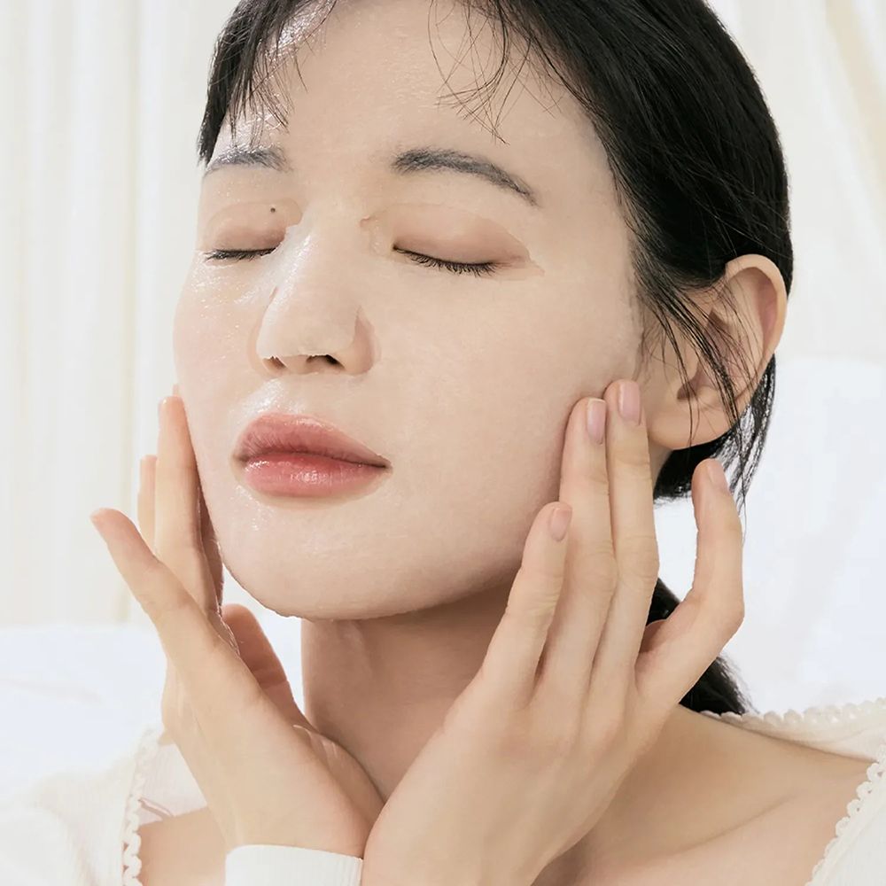 Donna con occhi chiusi indossa una maschera in tessuto, mani sul viso.