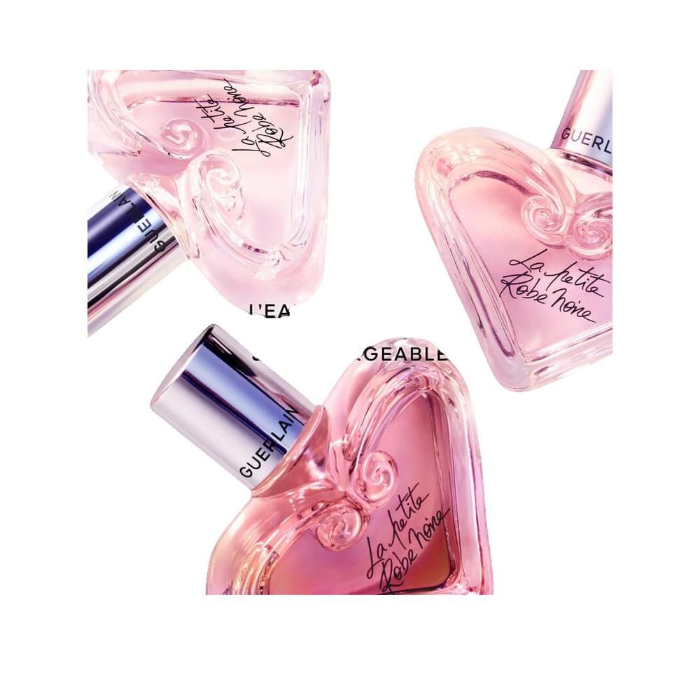 Tre flaconi rosa a forma di cuore con tappi argentati. Scritta: La petite Robe noire. Marchio: Guerlain.