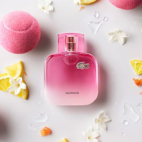 Flacone rosa con vaporizzatore, circondato da fiori e palline da tennis. Testo: Eau Fraiche.