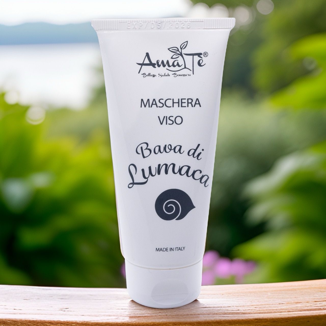 Tubo bianco con logo Amatè e testo: Maschera Viso Bava di Lumaca. Sfondo: legno e natura.