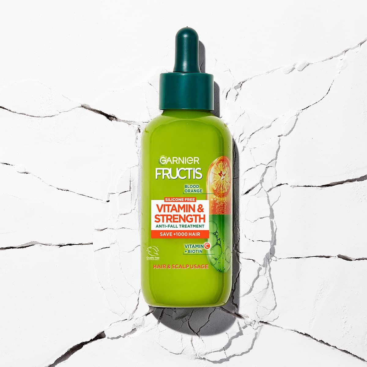 Flacone verde con contagocce. Scritta: Garnier Fructis Vitamine & Forza. Trattamento anticaduta. Contiene Vitamina C & Biotina.