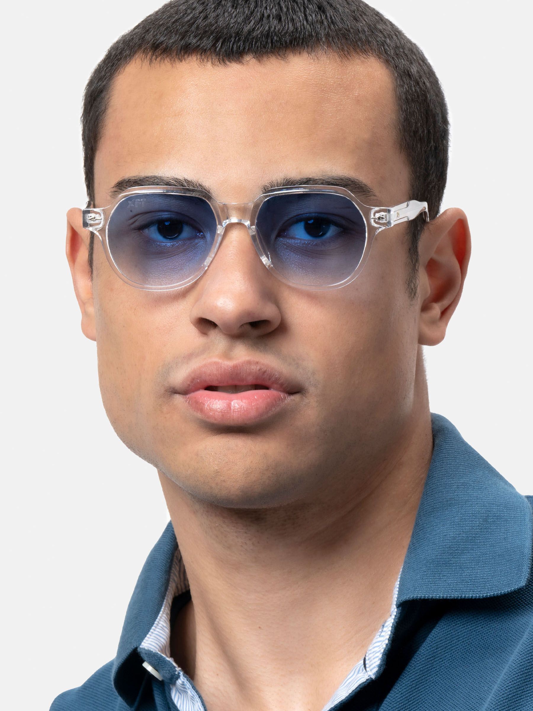 Primo piano di un uomo che indossa occhiali da sole con montatura trasparente e lenti blu.