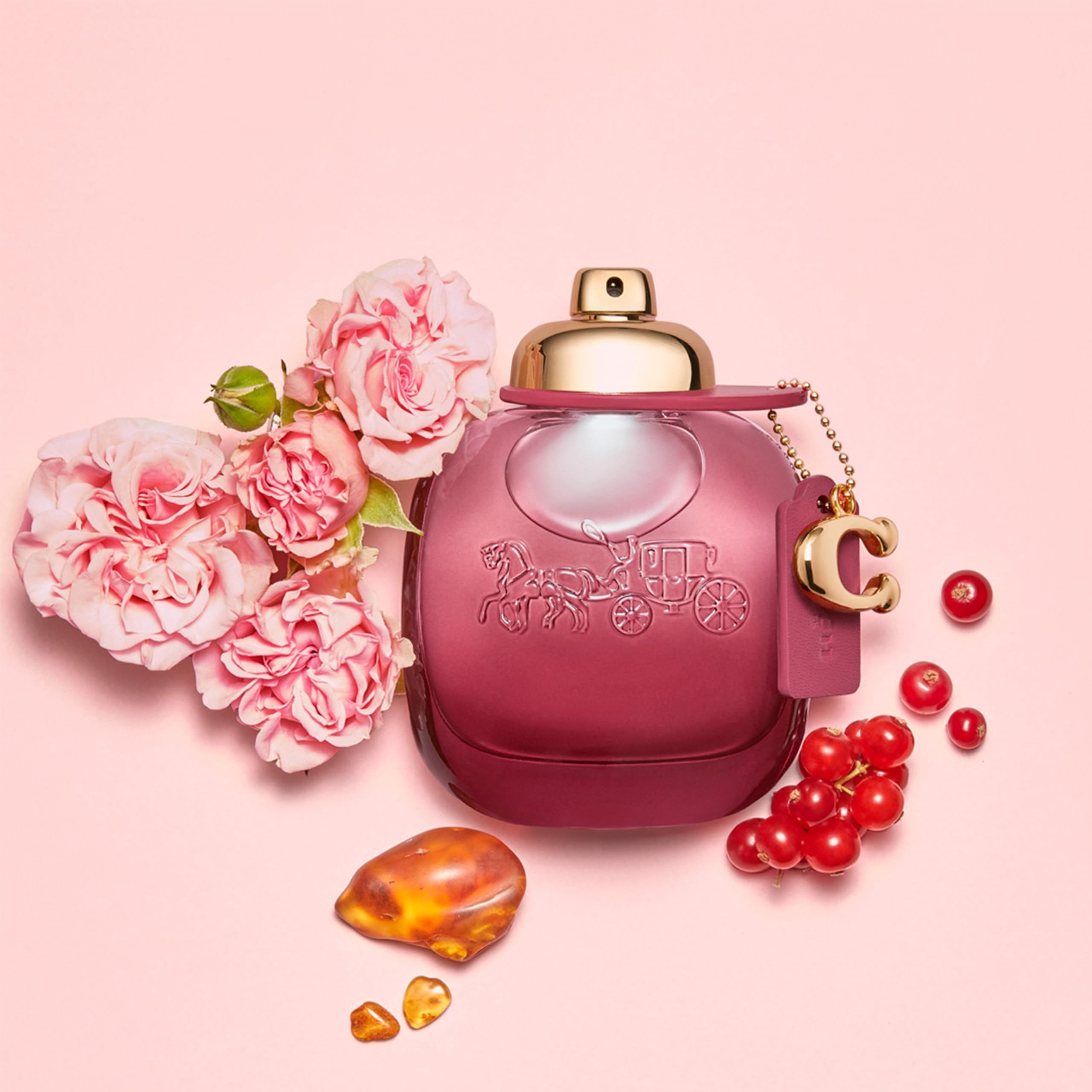 Coach Wild Rose EdP Nat. Spray. Flacone rosa con fiori, bacche e ambra. Tappo dorato.