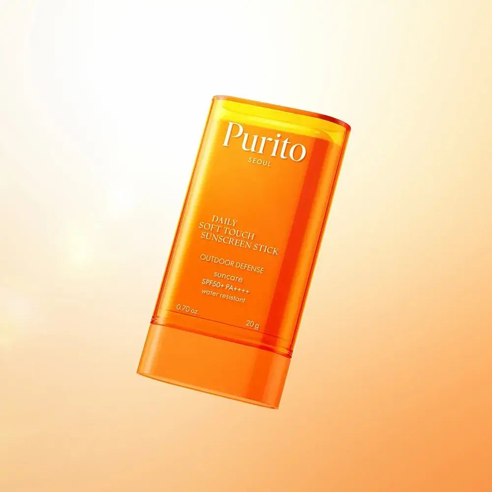 Stick trasparente arancione con estremità bianca. Testo: PURITO, Daily Soft Touch Sunscreen Stick.