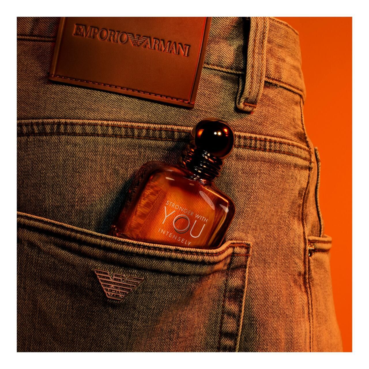 Emporio Armani Stronger With You Intensely. Flacone in tasca di jeans. Etichetta in pelle marrone con logo.
