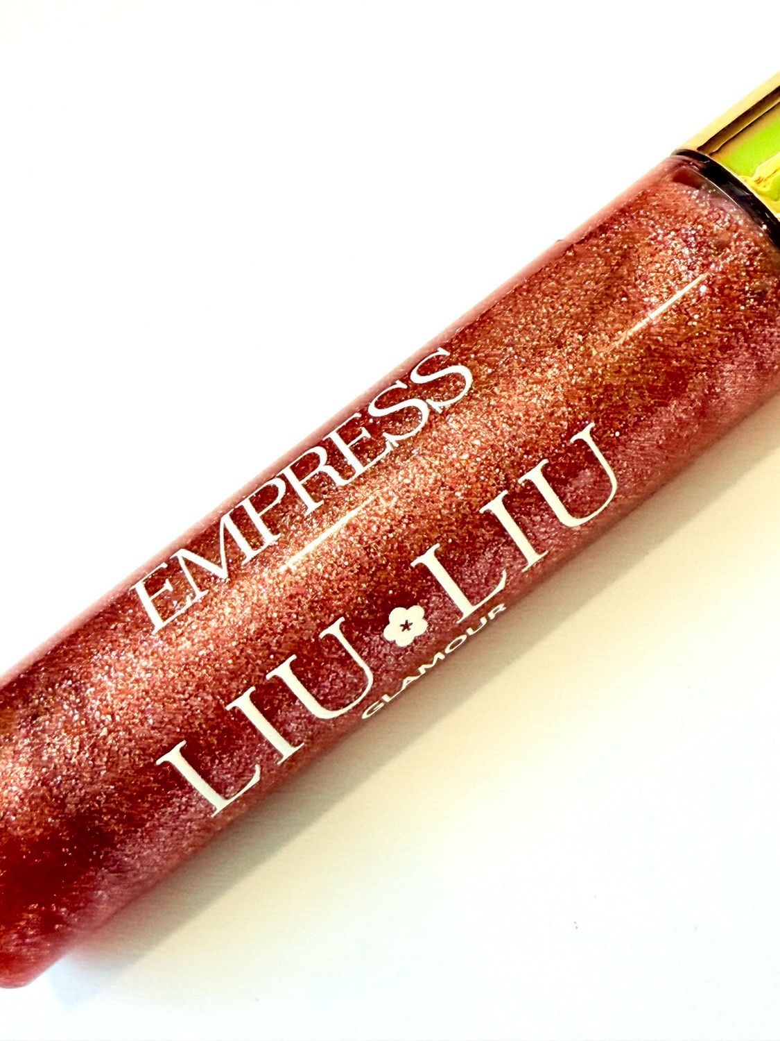 Primo piano del flacone di lucidalabbra. Scritta: EMPRESS LIU LIU Glamour. Lucidalabbra rosso glitterato.