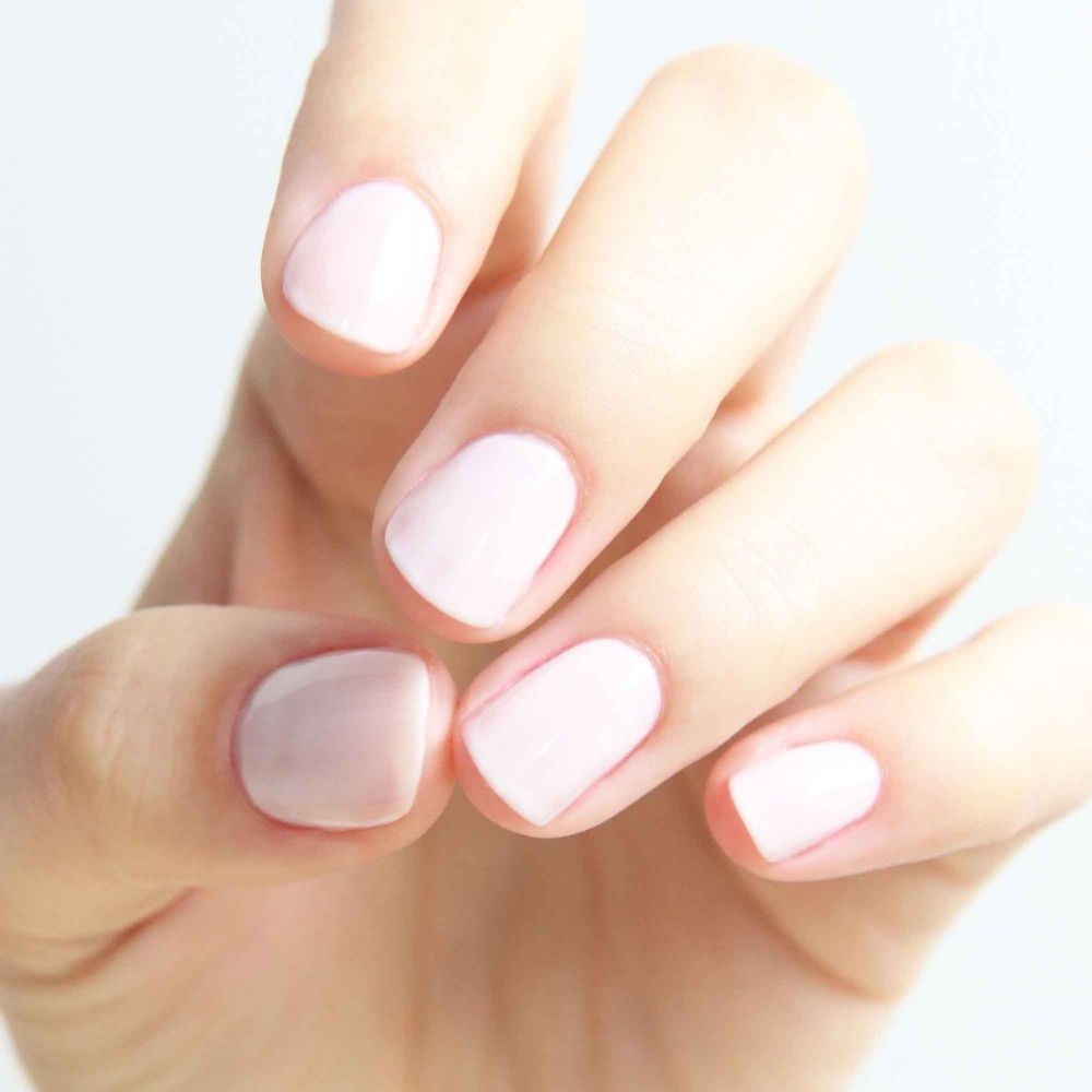 Mano con unghie smaltate di rosa chiaro. Diverse tonalità di rosa sulle unghie.