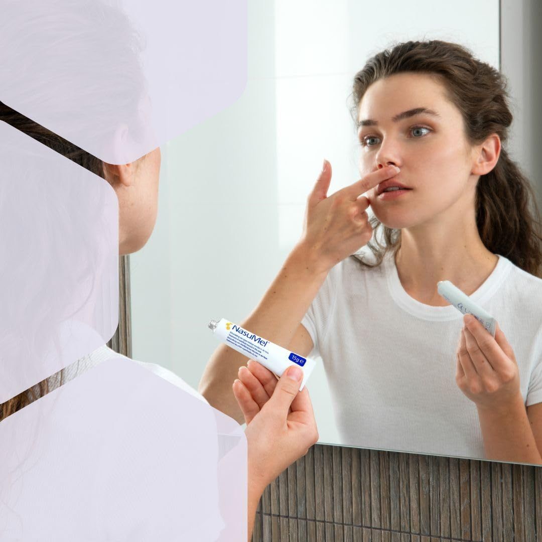 Donna si guarda allo specchio. Tiene un tubetto di NasuMel e si tocca il naso.