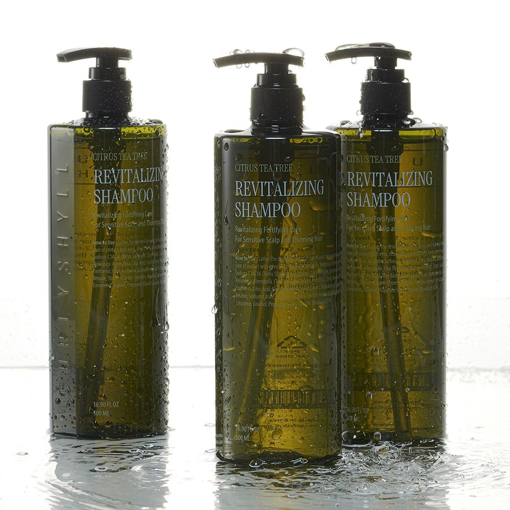 Tre flaconi di shampoo verdi con dosatori neri. Acqua sui flaconi. Scritta: Revitalizing Shampoo.