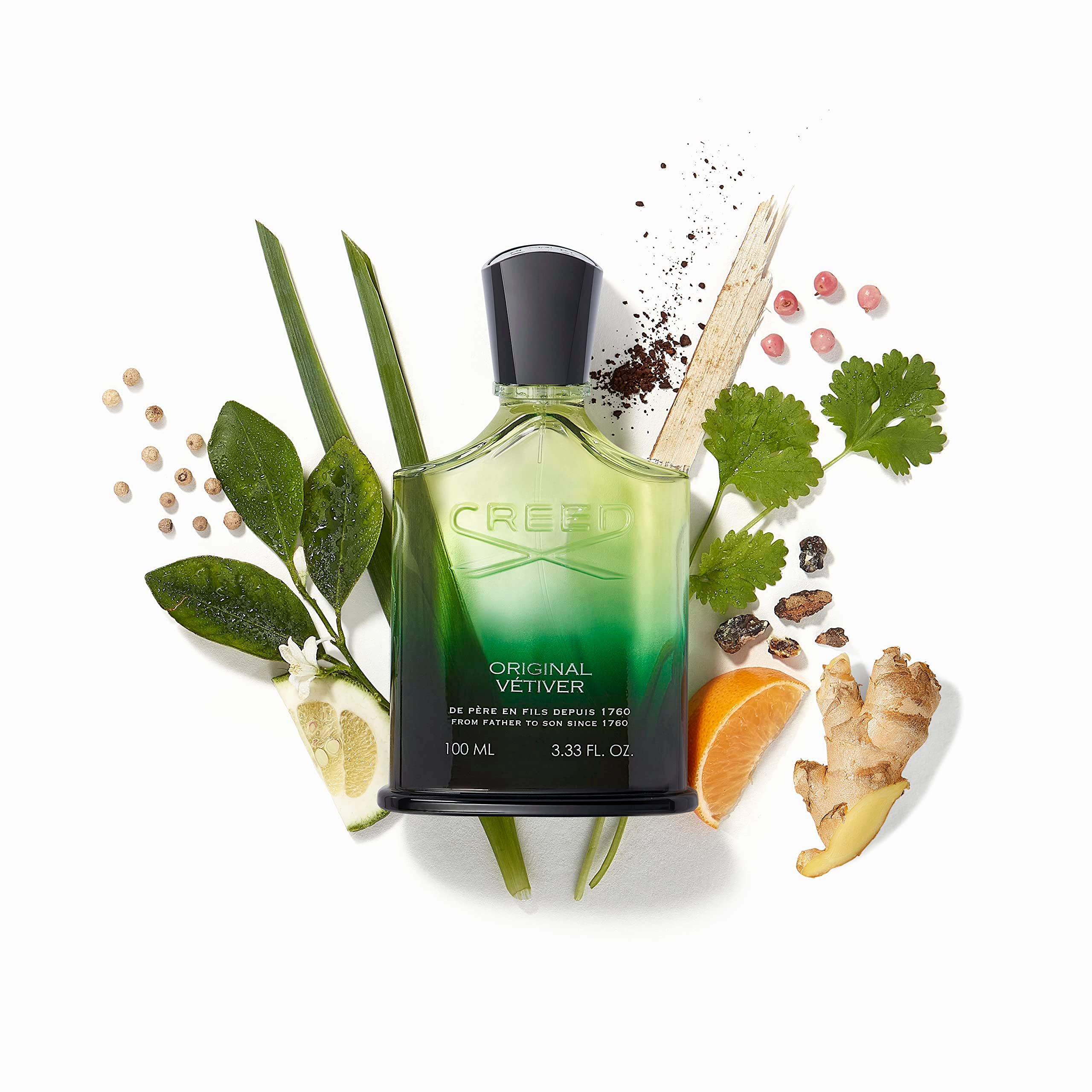 Flacone di profumo in vetro verde con tappo nero, circondato da ingredienti. Scritta: CREED ORIGINAL VETIVER. 100 ML.
