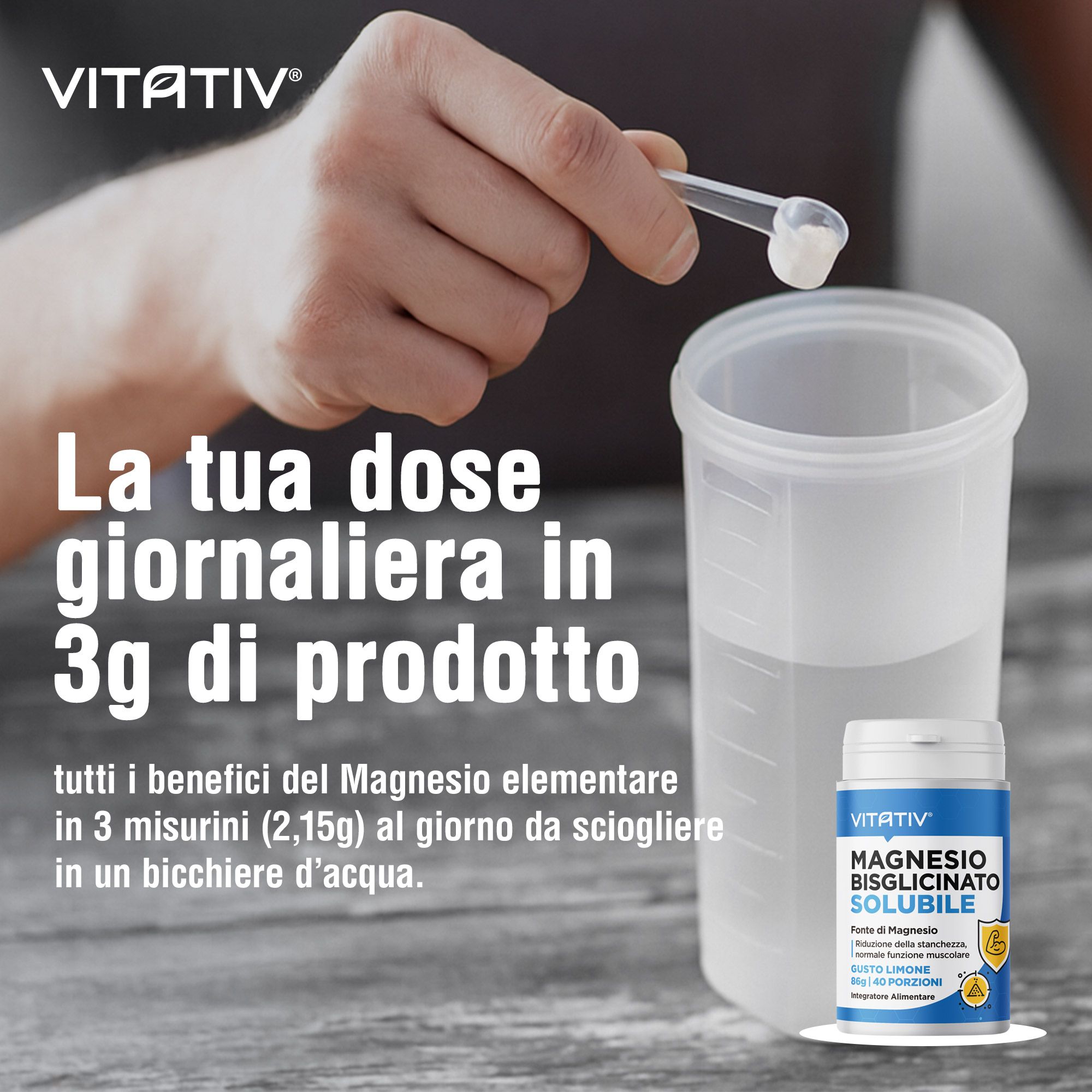 Una mano tiene un misurino con polvere bianca sopra un bicchiere graduato con acqua. Accanto, un piccolo barattolo blu di polvere di bisglicinato di magnesio.