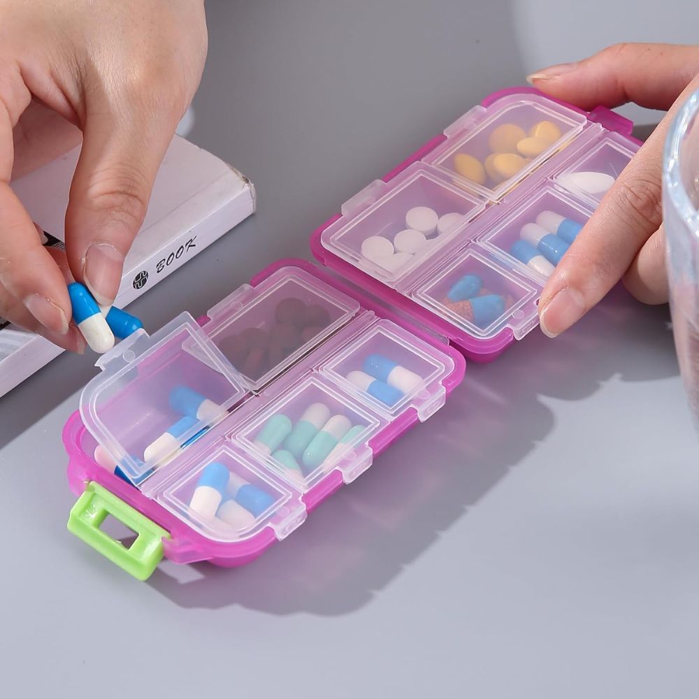 Portapillole rosa a 8 scomparti, riempito con varie pillole e capsule.