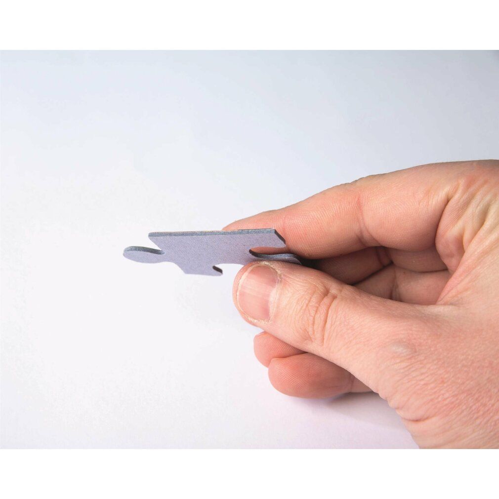 Pezzo di puzzle grigio, tenuto da una mano. Forma di un pezzo di puzzle. Colore grigio. Su sfondo bianco.