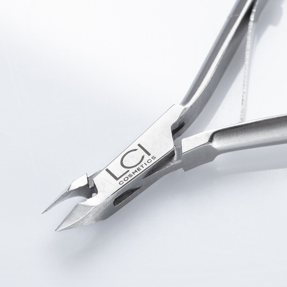 Primo piano della tronchesina per cuticole. Logo LCI Cosmetics ben visibile. Finitura metallica. Lama affilata. Su sfondo bianco.