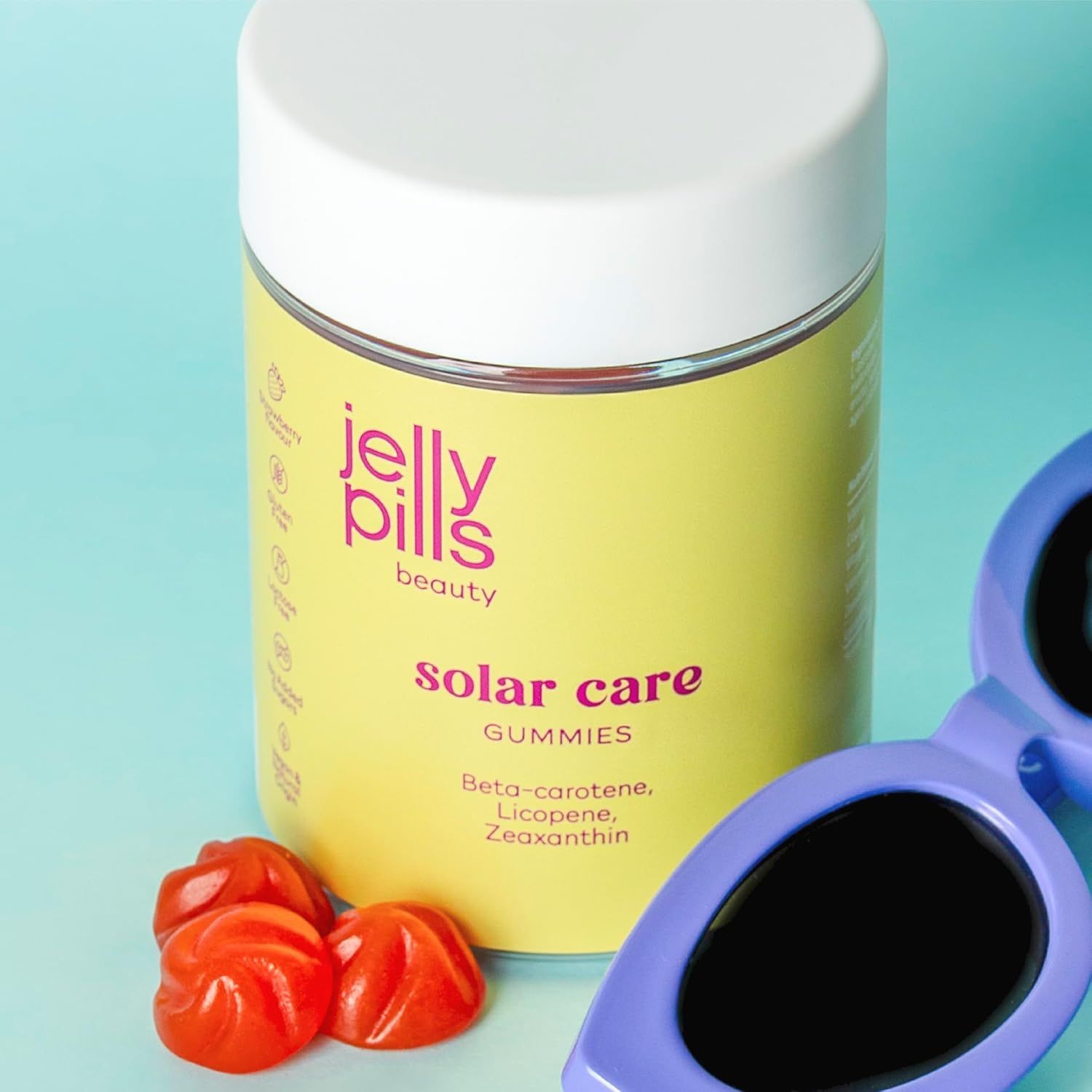 Barattolo di Jelly Pills Solar Care Gummies. 60 caramelle gommose. Scritta: Beta-carotene, licopene, zeaxantina. Occhiali da sole accanto. Sfondo blu.