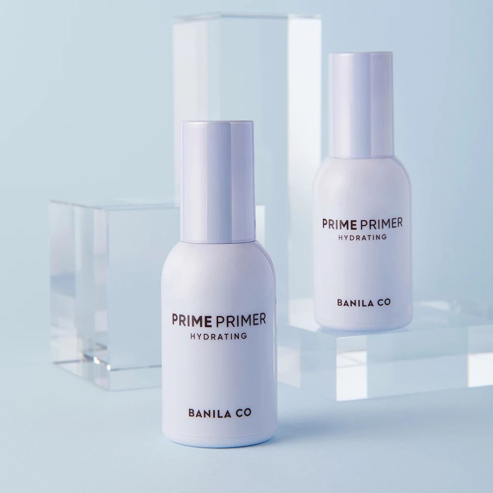 Due flaconi bianchi con dosatori a pompa. Scritta: PRIME PRIMER HYDRATING, BANILA CO. Su sfondo blu.