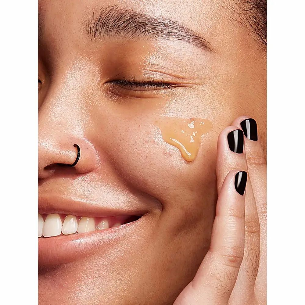 Donna con siero sulla pelle. Unghie nere. Prodotto non visibile. Applicazione non descritta.