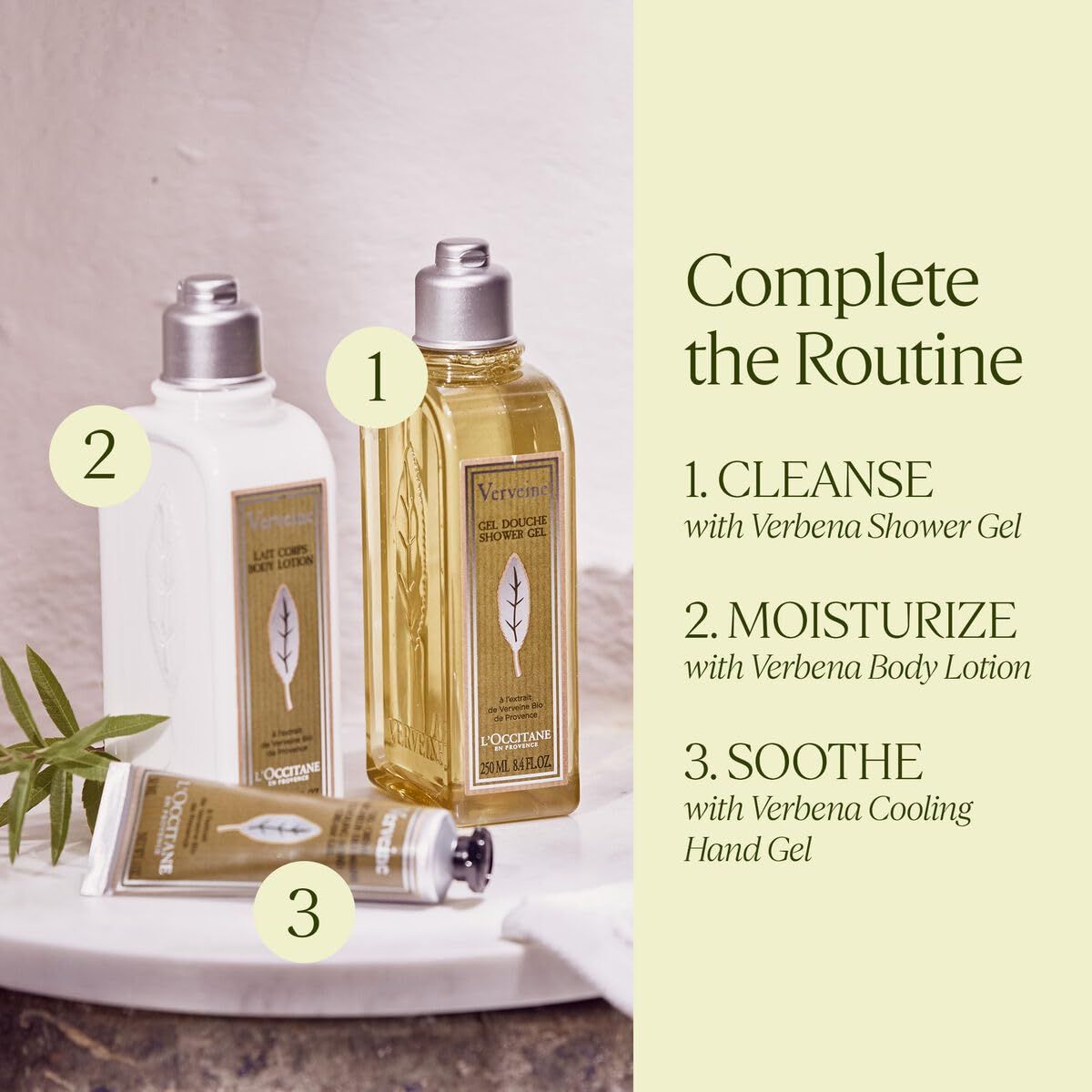Tre prodotti L'Occitane: gel doccia, lozione per il corpo e gel per le mani. Testo: 'Complete the Routine'.