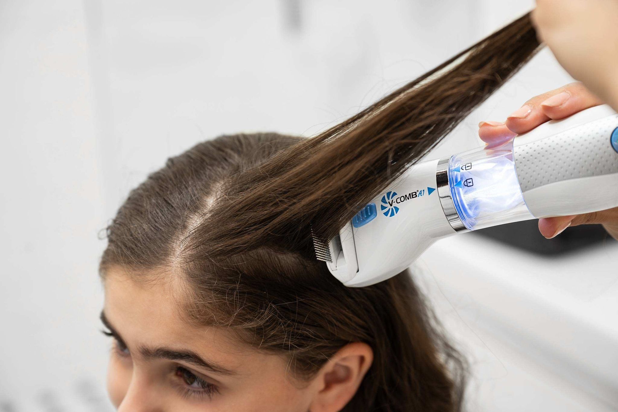 Pettine elettrico per pidocchi bianco e blu utilizzato sui capelli di un bambino.