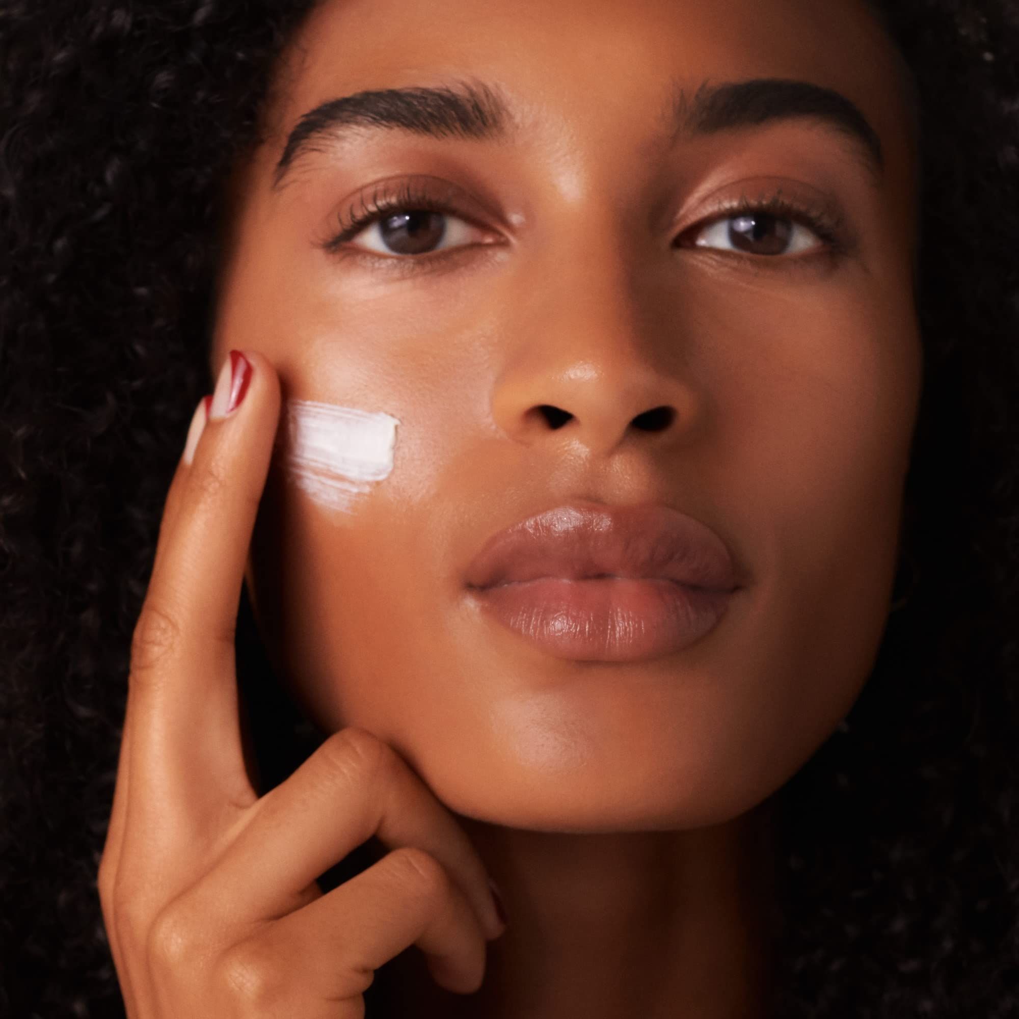 Donna applica crema. Primo piano. Cura della pelle. Crema applicata sul viso.