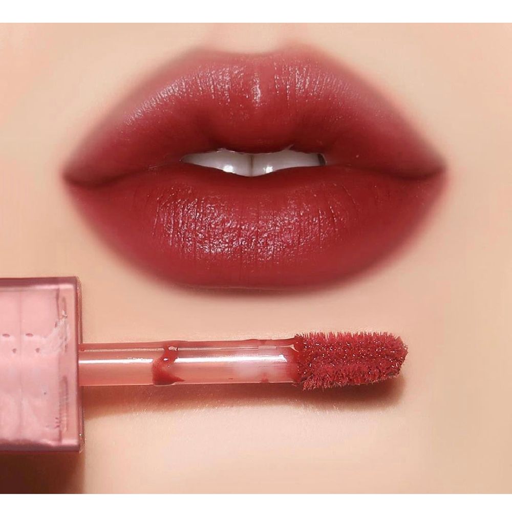 Primo piano di labbra con lucidalabbra rosso scuro applicato. Un applicatore è visibile.