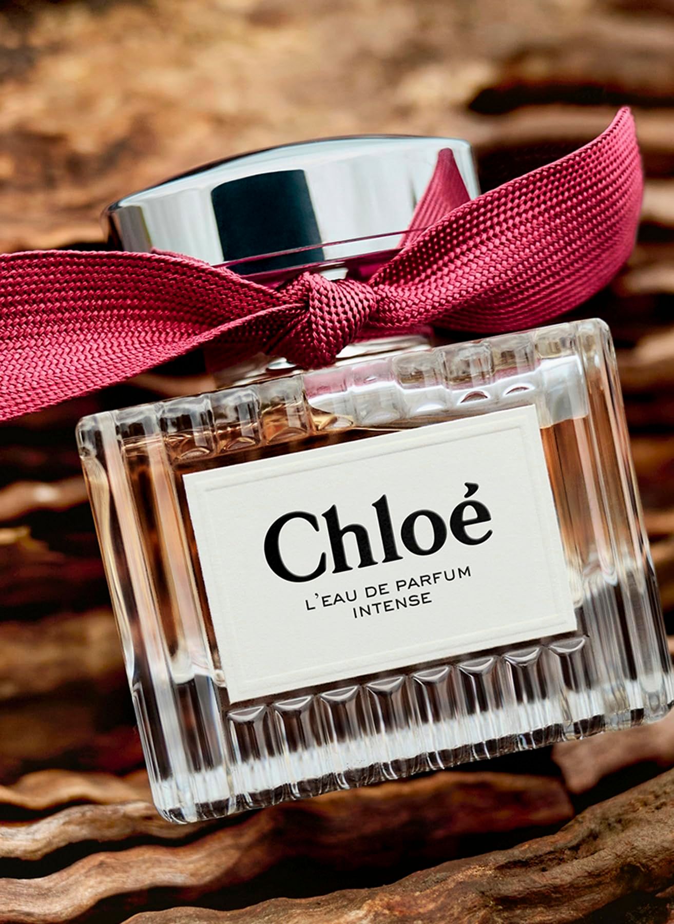 Flacone, tappo argentato, fiocco rosso. Etichetta "Chloé L'EAU DE PARFUM INTENSE".