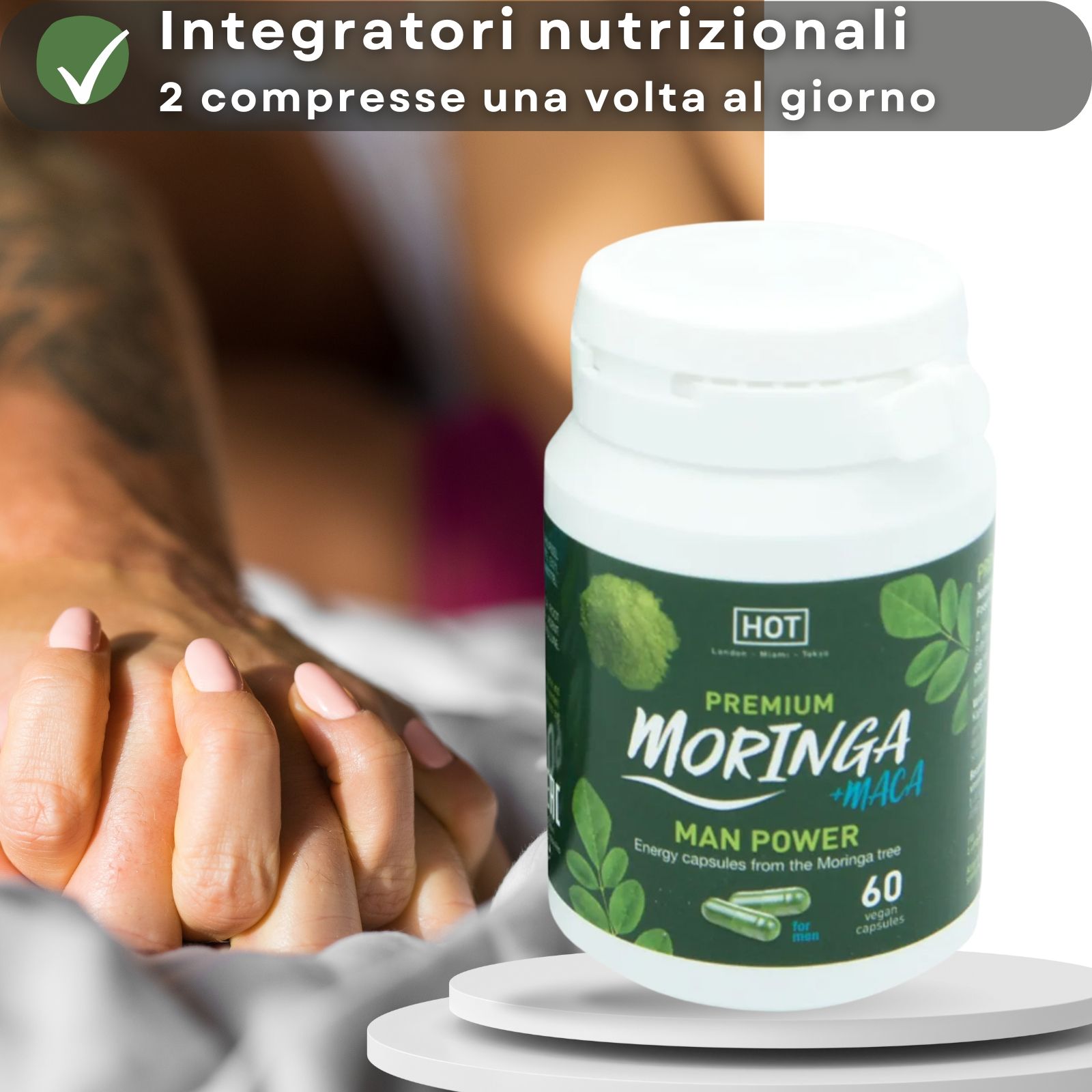 Una mano tiene una capsula blu accanto a un flacone Moringa + Maca. 60 capsule.