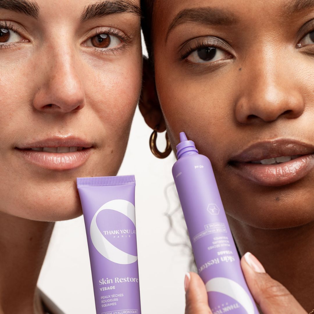 Due donne tengono tubi lilla. Scritta: THANK YOU LAB PARIS. Nome prodotto: Skin Restore Visage.