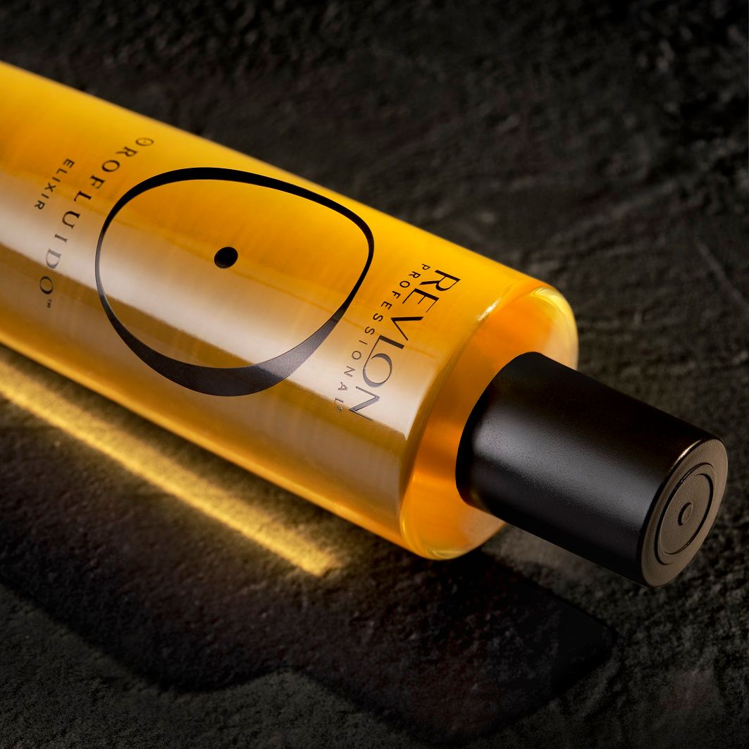 Flacone con tappo nero su superficie scura. Scritta: Revlon Professional, Orofluido Elixir. Liquido giallo.