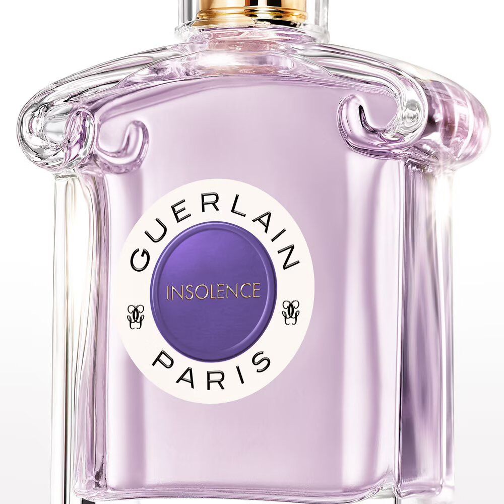 Flacone in vetro con liquido viola. Etichetta "GUERLAIN INSOLENCE PARIS". Tappo dorato. Spruzzatore trasparente.
